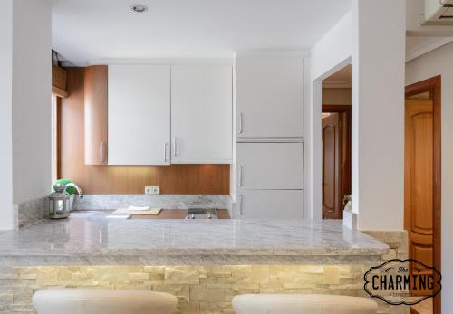 a kitchen with white cabinets and a marble counter top at Charming Argüelles in Madrid
