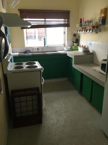 a kitchen with green cabinets and a stove top oven at Ocean View Apartments in Flying Fish Cove