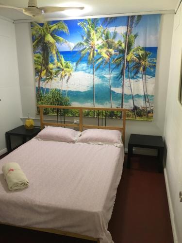 ein Schlafzimmer mit einem Wandbild von Palmen in der Unterkunft Ocean View Apartments in Flying Fish Cove