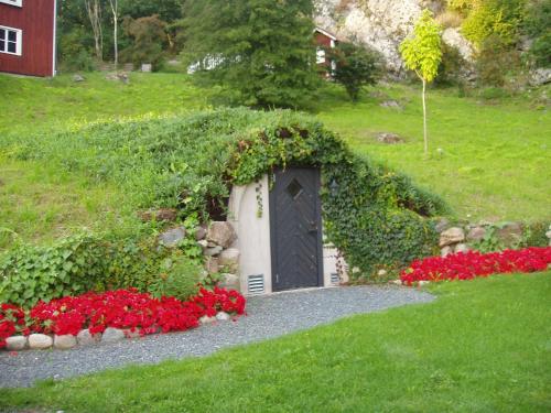 a door in a hedge with red flowers in a yard at Brunstorpsgård Bränneriet in Huskvarna