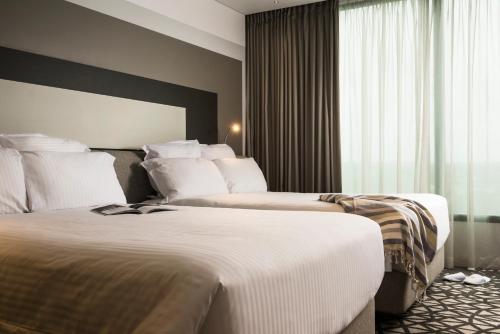 a hotel room with two beds and a window at Pullman Sydney Airport in Sydney