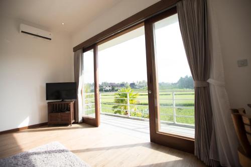 a room with a large sliding glass door with a television at The Samara Villas & Restaurant in Ubud