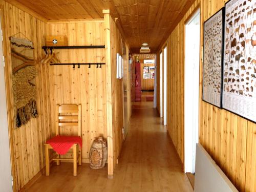 a hallway of a house with wooden walls and a red chair at Stora Björnstugan in Laisvall