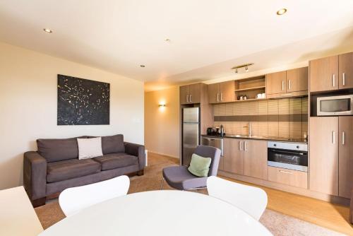 a living room with a couch and a kitchen at Edgewater Palms Apartments in Paihia