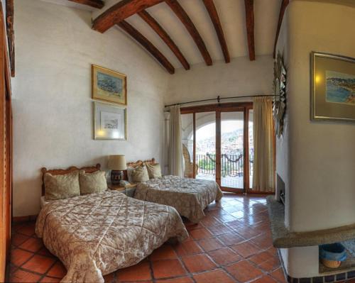 a bedroom with two beds and a balcony at Posada de la Mision, Hotel Museo y Jardin in Taxco de Alarcón