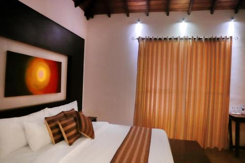 a bedroom with a bed and a window with a curtain at Blue Water Boutique Hotel in Negombo