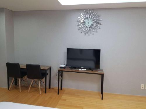 a room with a television and a table with chairs at Sky Guestel in Incheon