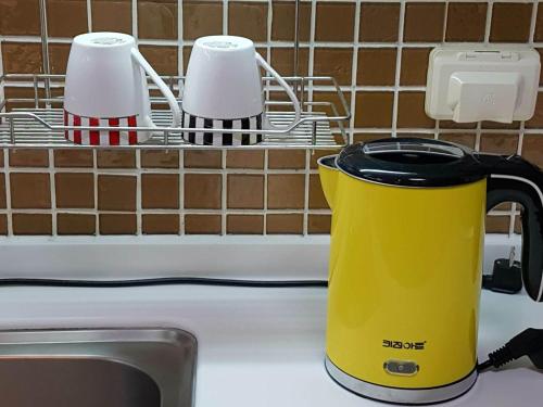 a yellow kettle on a counter next to a sink at Sky Guestel in Incheon