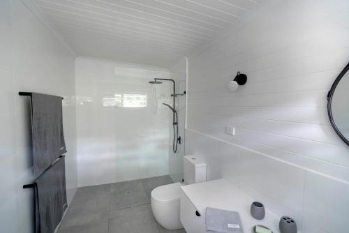 a white bathroom with a toilet and a mirror at mist at Cape Tribulation in Cape Tribulation