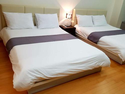 two beds sitting next to each other in a room at Sky Guestel in Incheon