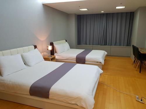una camera d'albergo con due letti e un tavolo con sedie di Sky Guestel a Incheon