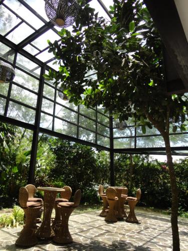 a glassconservatory with tables and chairs and a tree at Abagatan ti Manila in Alfonso