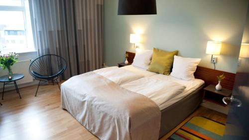 a bedroom with a bed with white sheets and yellow pillows at Hotel Svendborg in Svendborg