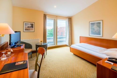 a hotel room with a bed and a desk and a television at Best Western Hotel Geheimer Rat in Magdeburg