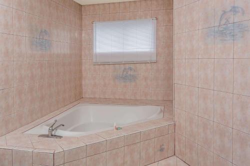 a bath tub in a tiled bathroom with a window at Travelodge by Wyndham San Clemente Beach in San Clemente