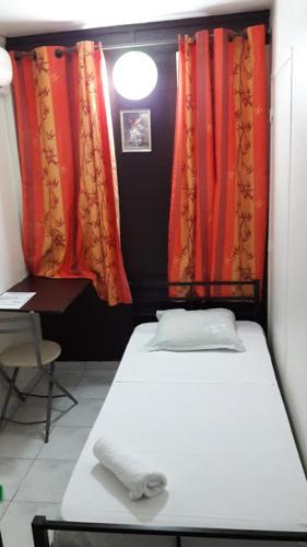 a small room with a bed and red curtains at Hôtel Du Centre in Saint-Denis