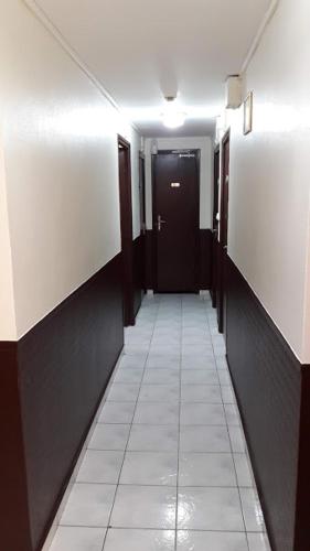a hallway with a black door and a white tile floor at Hôtel Du Centre in Saint-Denis
