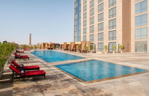 أسكوت رافال العليا الرياض في الرياض: مسبح مع كراسي جلوس امام مبنى