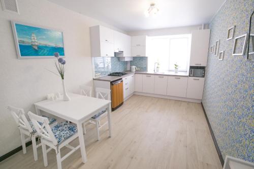 Una cocina con gabinetes blancos y una mesa y sillas. en Elegant VIP apartment, en Sumy
