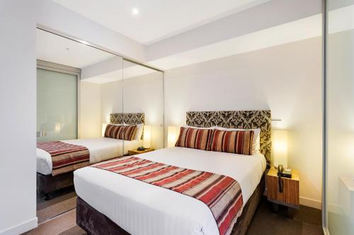 a hotel room with two beds and two lamps at Seasons Heritage Melbourne in Melbourne