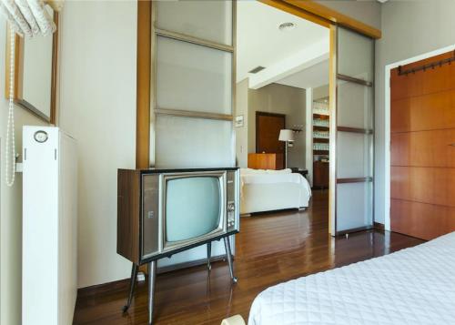 a television in a room with a bed and a bedroom at SKAMAShouse in Athens