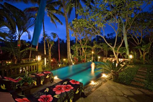 a swimming pool in a resort at night at The Mahogany Villa Ubud in Tegalalang