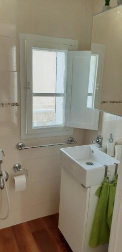 a white bathroom with a sink and a window at Il sogno di Ele in Polignano a Mare