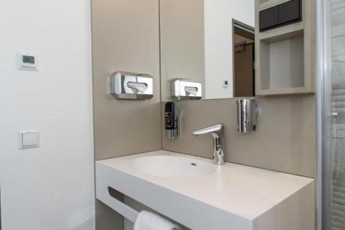 a white bathroom with a sink and a mirror at Hotel Goldenes Rad in Ulm