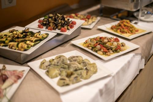a buffet with several plates of food on a table at Hotel Luna Bianca Folgaria in Folgaria