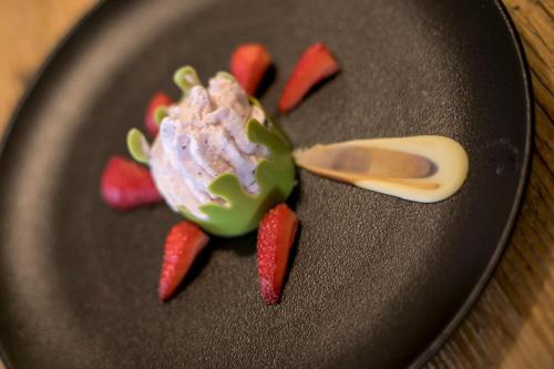 a black plate with ice cream and strawberries on it at Hotel Luna Bianca Folgaria in Folgaria