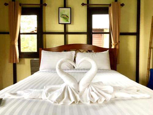 two white swans making a heart on a bed at Baan Thung Home Stay in Prasat