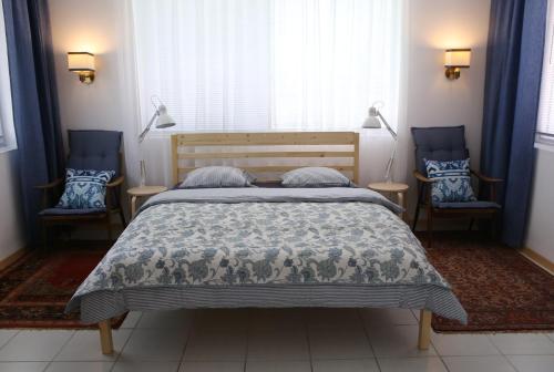 a bedroom with a bed and two blue chairs at Sára Vendégház in Szentes