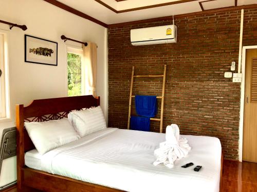 a bed in a room with a brick wall at Baan Thung Home Stay in Prasat