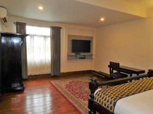a bedroom with a bed and a flat screen tv at The Heritage Club - Tripura Castle Hotel and Spa in Shillong