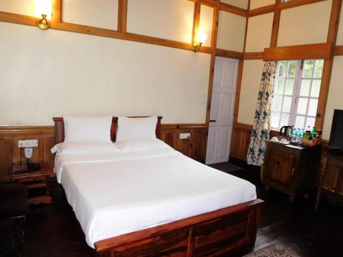 a bedroom with a bed with white sheets and a window at The Heritage Club - Tripura Castle Hotel and Spa in Shillong