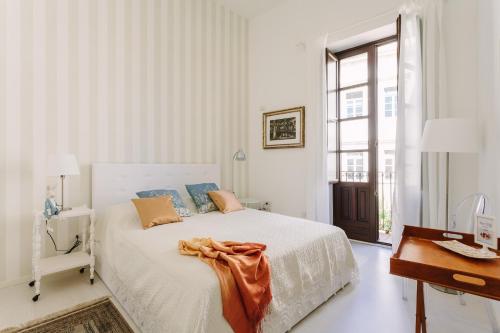 een witte slaapkamer met een bed en een bureau bij Suite La Piazza by Wonderful Italy in Siracusa