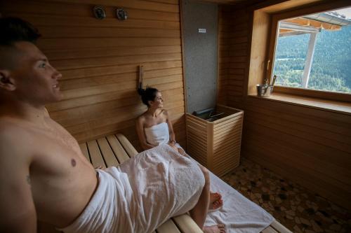 a man and a woman in a sauna at Hotel Luna Bianca Folgaria in Folgaria
