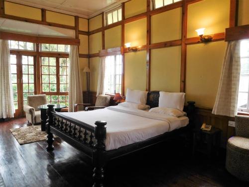 a bedroom with a large bed in a room with windows at The Heritage Club - Tripura Castle Hotel and Spa in Shillong