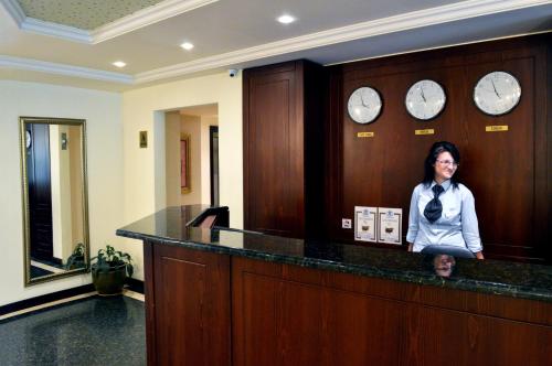 a woman standing behind a counter in a room with clocks at Aparthouse Borovo near Bulgaria Mall, free street parking in Sofia