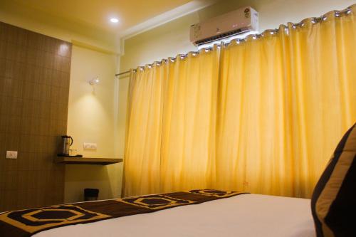 a bedroom with a bed and a yellow curtain at Solitaire Hotel And Resorts in Ujjain