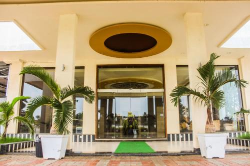a building with two palm trees in front of it at Solitaire Hotel And Resorts in Ujjain