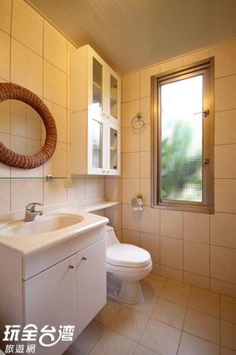 a bathroom with a toilet and a sink and a mirror at 拇指園民宿 in Guanxi