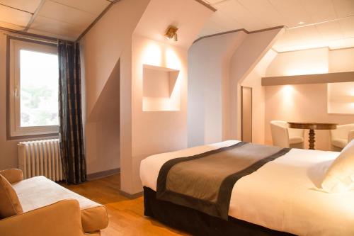 ein Hotelzimmer mit einem Bett und einem Stuhl in der Unterkunft The Originals Boutique, Hôtel du Pont Roupt, Mende (Inter-Hotel) in Mende