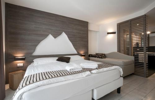a bedroom with a large white bed and a couch at Hotel Luna Bianca Folgaria in Folgaria