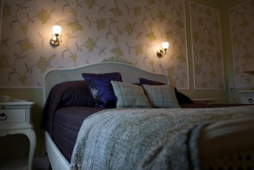 a bedroom with a bed and two lights on the wall at The Falcon Hotel in Farnborough