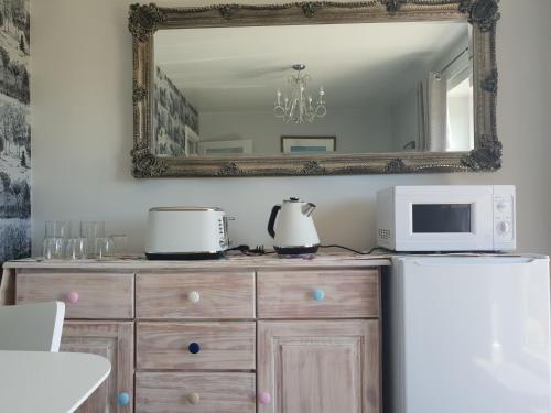 a mirror above a dresser with a microwave and a refrigerator at Goshens Farm B&B in Wootton