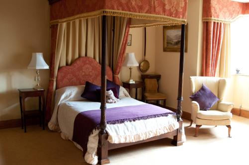 a bedroom with a canopy bed and a chair at Lullington House in Frome