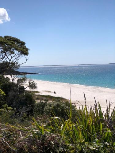 a beach with a person on the sand and the ocean at Quelle Vue Huskisson in Huskisson