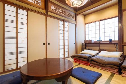 a room with a table and a bed and windows at Guest House Enishi in Toyama
