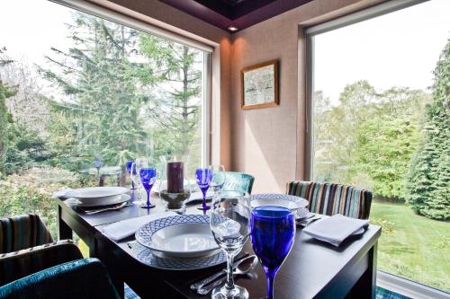 a table with wine glasses on it with a large window at Tir y Coed Country House in Conwy